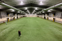 One person walks across an empty field inside the Dimond Park Field House.