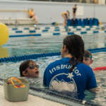 Swim Lessons_2025 (5) A water instructor teaches kids how to swim at the Dimond Park Aquatic Center.ย