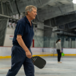 A person holds a pickleball paddle while playing in Treadwell Arena.