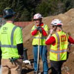 Staff from U.S. Army Corps of Engineers and City and Borough of Juneau talk while digging sand.