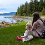 A mother and daughter sit on the grass at Jensen-Olson Arboretum.