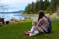 A mother and daughter sit on the grass at Jensen-Olson Arboretum.