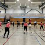 IMG_0564 (1) A group of women playing volleyball in a gym.
