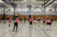A group of women playing volleyball in a gym.