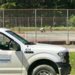IMG_1505 (1) A Parks & Recreation maintenance truck parked outside of the outdoor Floyd Dryden tennis and pickleball courts. Two staff inspect the court.