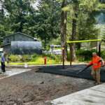 Two contractors walk around Sigoowu Ye Park as they work on the park’s new surfacing.