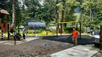 Two contractors walk around Sigoowu Ye Park as they work on the park’s new surfacing.
