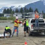 Four people wearing safety vests load a truck with sandbags.