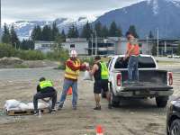 Four people wearing safety vests load a truck with sandbags.