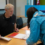 An election worker helps a voter get ready to vote.