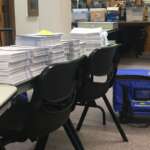 election-ballots-10.7.20 Several stacks of ballots sit on a table.