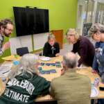 A group of people chat while sitting around a table.