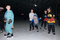 Kids wearing costumes skate on ice.