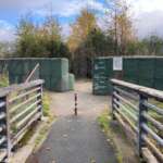 Bridge entrance and paved pathway with flood barriers in the background