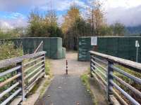 Bridge entrance and paved pathway with flood barriers in the background